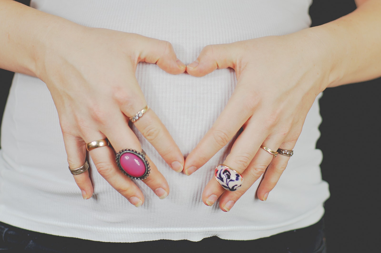 Kobieta, tworząca znak serca na brzuchu. Ciąża, miłość.