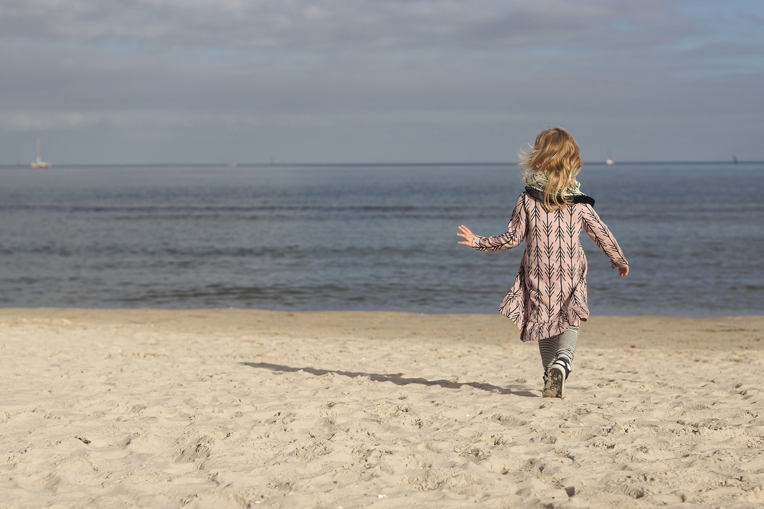 Ostatni ciepły weekend nad morzem - dziecko spoglądające na wodę w różowej sukience